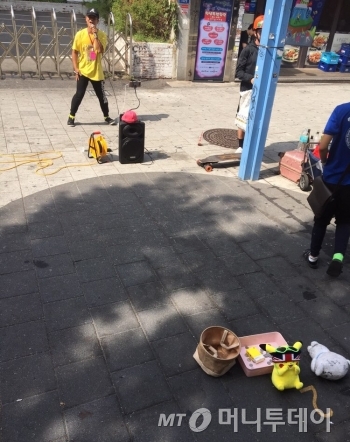 홍대 길거리에서 김건모의 ‘잘못된 만남’을 공연하고 있는 청년. 클라이막스로 갈수록 더 많은 웃음을 준다. 그의 개성이 좋아 공연 모금함에 노란색 비타민 한상자를 넣었다./사진=남형도 기자