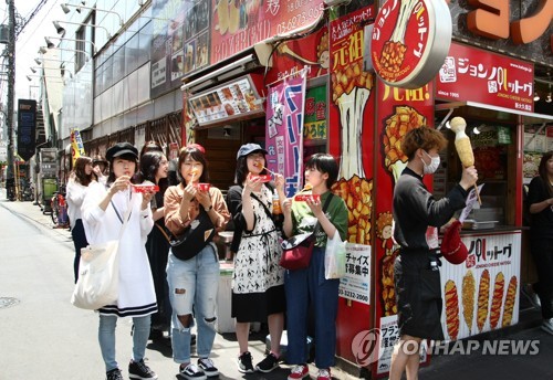 일본 도쿄 신주쿠의 한인타운 신오쿠보(新大久保)에서 일본 젊은이들이 요즘 최고 인기인 한국 길거리 치즈 핫도그 '아리랑 핫도그'를 먹으며 즐거워 하는 모습 [연합뉴스 자료사진]