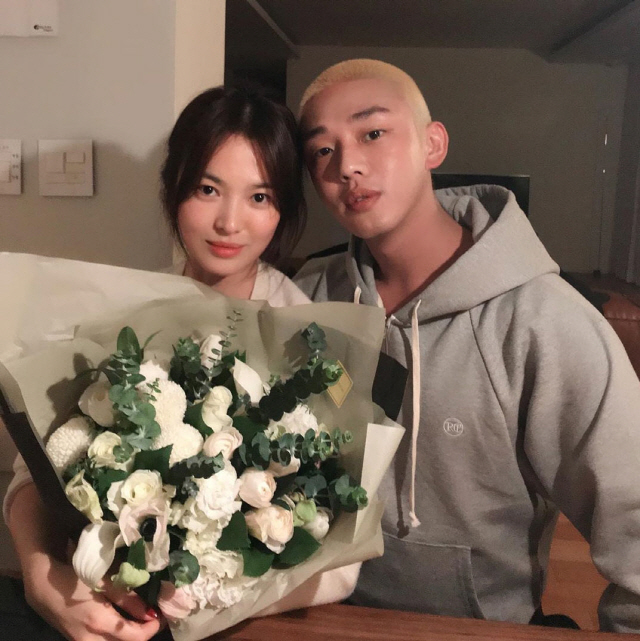 Friendly images of Actor Song Hye-kyo and Yoo Ah-in have been released.Yoo Ah-in posted a picture on his 22nd day with an article entitled LONG LIVE THE QUEEN.Inside the picture is a picture of Yoo Ah-in and Song Hye-kyo; Song Hye-kyo holding a bouquet of flowers in his arms.A beautiful visual than flowers attracts Eye-catching.In a comfortable outfit of a grey hooded T-shirt, the charismatic look of Yoo Ah-in, who dyed her short-cut hair yellow, also focused on Eye-catching.In particular, Song Hye-kyo, who is making a bright smile in another photo, and Yoo Ah-in, who is leaning slightly on such Song Hye-kyo, attracted attention at once.