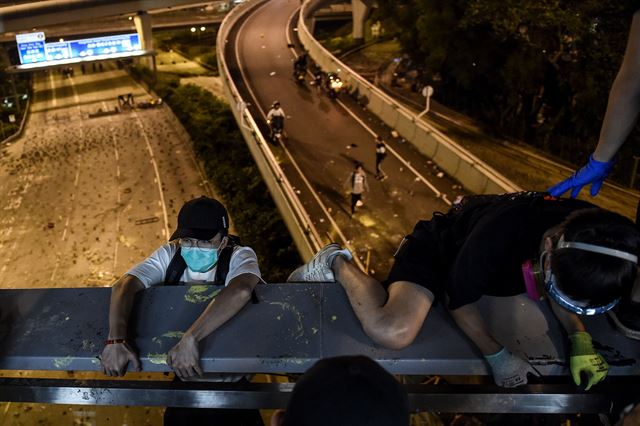 11월18일 홍콩 폴리테크닉 대학과 경찰로부터 탈출하기 위해 시위대들이 고가다리에서 고속도로 위로 밧줄을 타고 내려가고 있다. AFP 연합뉴스