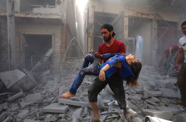 5월26일 시리아 이들립 지방에서 한 남자가 폭격으로 부상당한 어린이를 안고 이동하고 있다. 이날 정부군의 공습으로 12명의 시민이 목숨을 잃었다. AFP 연합뉴스