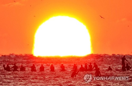 새해 일출 서핑 (양양=연합뉴스) 2020년 새해 첫날 강원 양양 죽도해변에서 열린 '일출 서핑 이벤트'에 참여한 서퍼들이 바다 위에서 보드에 몸을 실은 채 수평선 위로 떠오르는 태양을 맞이하고 있다. 2020.1.1  [양양군서핑연합회 제공.재판매 및 DB금지]