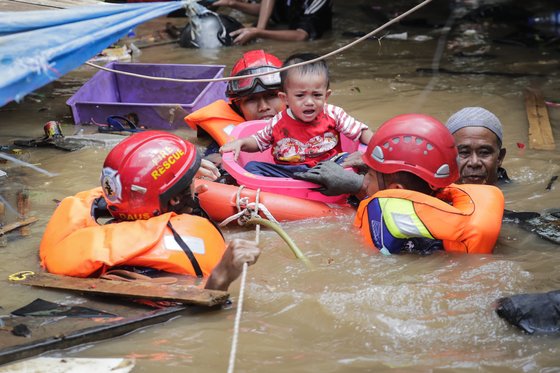 인도네시아 소방대원들이 2일(현지시간) 자카르타 도심의 한 가옥에서 어린이를 구조하고 있다..[EPA=연합뉴스]
