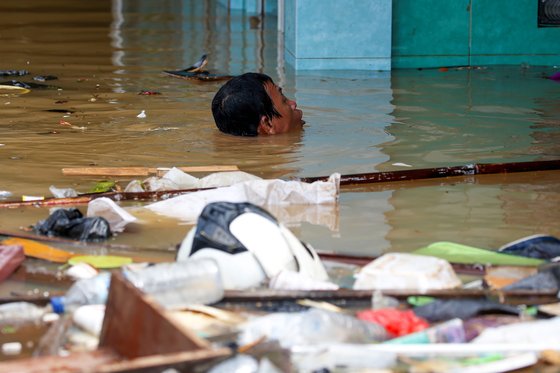 한 남성이 2일 자카르타 도심에서 수영을 해 집으로 향하고 있다. [로이터=연합뉴스]