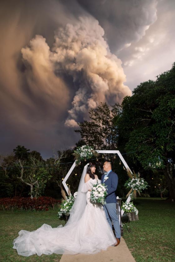 12일 화산재를 분출하는 탈 화산을 배경으로 결혼식을 올린 치노 배플러·캣 배플러 부부.<출처=CNN, 랜돌프 에번 트위터 />© 뉴스1