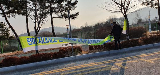 충남 아산시 경찰인재교육원 입구에 붙은 '편하게 지내시고 건강하게 귀가하시기 바랍니다'라는 내용의 현수막을 한 주민이 철거하고 있다. 프리랜서 김성태