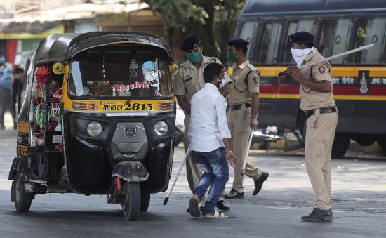 25일 인도 뭄바이에서 '전국 봉쇄령'을 위반하고 집밖에 나온 사람들을 혼내고 있다. AP연합뉴스