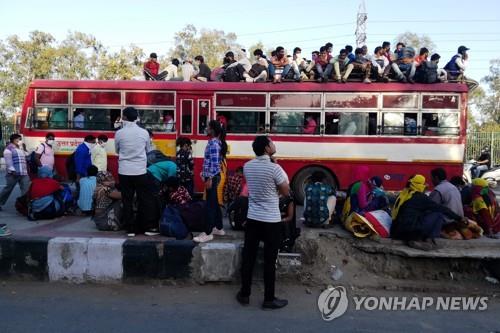 28일 고향으로 돌아가기 위해 인도 수도 뉴델리의 버스정류장에서 버스 위까지 올라탄 일용직 근로자와 가족들. [AFP=연합뉴스]