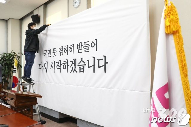 (서울=뉴스1) 임세영 기자 = 김종인 미래통합당 총괄선대위원장의 제21대 국회의원 선거 결과 관련 입장 발표 기자회견에 앞서 16일 오전 서울 여의도 국회에 통합당 회의실에서 관계자가 백드롭을 교체하고 있다. 교체된 백드롭에는 '국민의 뜻 겸허히 받들어 다시 시작하겠습니다'라고 적혀있다. 2020.4.16/뉴스1