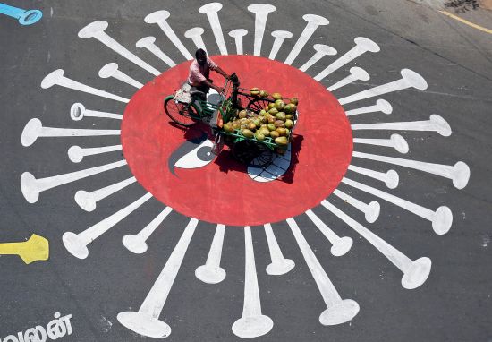 인도 남부 첸나이에서 14일(현지시간) 코로나19를 그래피티가 낙서된 도로 위를 자전거를 탄 시민이 지나가고 있다. 로이터연합뉴스