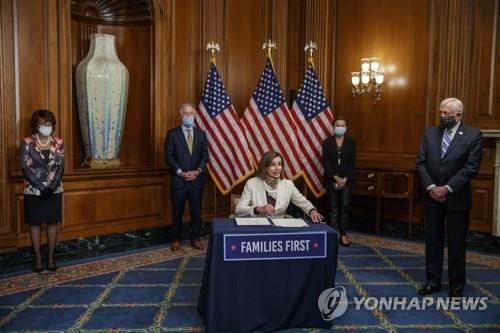 낸시 펠로시 미국 하원 의장이 신종 코로나바이러스 감염증(코로나19) 대응을 위해 긴급 편성된 4천840억 달러 규모의 추가 예산 법안에 대해 하원 승인 후 열린 서명식에 참여하고 있다. [EPA=연합뉴스]