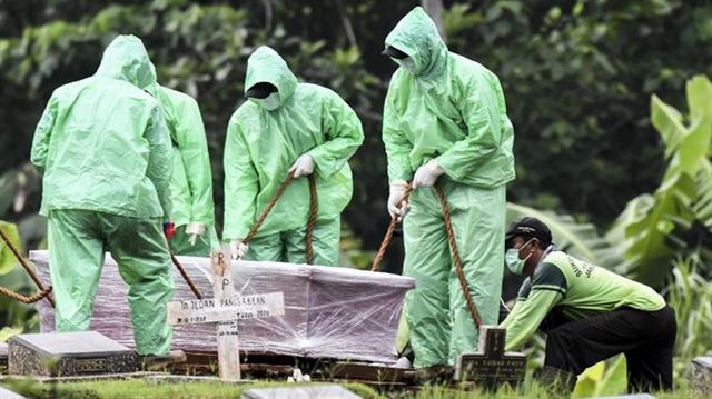 비옷을 입은 인도네시아 한 묘지 관리인들이 비닐로 꽁꽁 싸맨 코로나19 사망자의 관을 매장하고 있다. 안타라통신 캡처