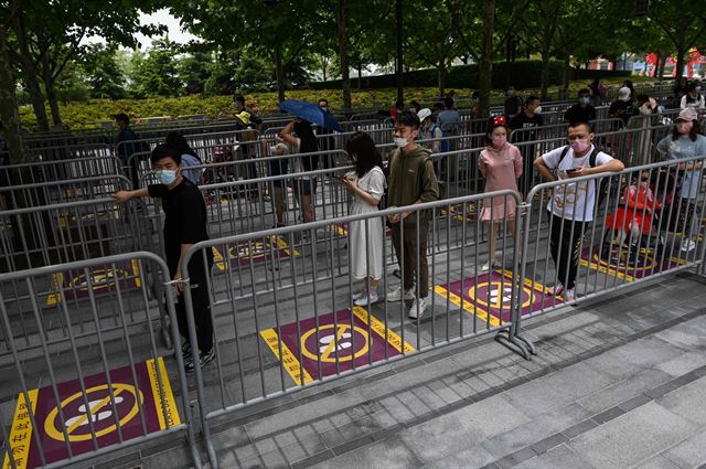 지난1월 코로나19 로 폐쇄되었던 중국 상하이 디즈니랜드가 3개월 반만에 재개장한 11일 마스크를 쓰고 상하이 디즈니랜드를 방문한 시민들이 사회적 거리두기를 유도하기 위해 바닥에 그려진 표시 뒤에 서서 입장을 기다리고 있다. 상하이=AFP 연합뉴스