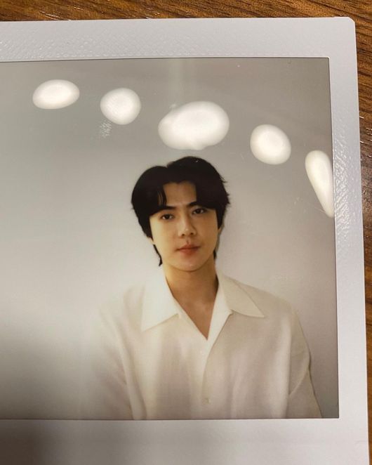 EXO Sehun showed off his unique physical.On the afternoon of the 22nd, EXO Sehun posted a selfie on his personal SNS.Sehun in the photo shoots a polaroid film wearing a white shirt. EXO Sehun shook the hearts of global fans with a neat 5:5 parting and clear features. Sehun also captivated the masculine beauty by loosening the top button of his shirt.The Pacific Ocean shoulder, the trademark of EXO Sehun, is also a must. Sehun, who has a shoulder that is too wide to be able to measure its length, made viewers admire with a body that was as good as a mannequin.Meanwhile, EXO Sehun released Chanyeol and Sehun & Chanyeols first full album 1 Billion Views in July.EXO Sehun SNS