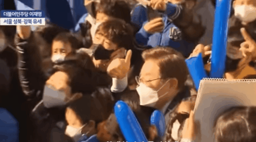 이재명 전 경기지사가 지난 3월 대선 기간 때 서울 성북·강북 유세 도중 시민들과 사진을 찍고 있다. 당시 영상에는 이 전 지사가 앞에 앉은 남성의 머리를 손으로 누르는 듯한 장면이 포착됐다. MBC 화면 캡처