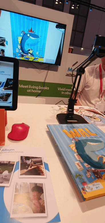 지난 5일(현지시간) 독일 베를린에서 열린 'IFA 2022' 아티젠스페이스 부스에서 그림책(사진 우측 하단)을 웹캠으로 비추자 연결된 TV(사진 상단)에 고래가 나타나 헤엄치는 모습을 시연하고 있다.