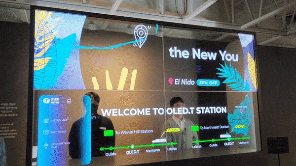 투명 OLED가 적용된 열차 인포메이션 카운터 모습. 투명 패널 뒤에 사람이 서있는 모습이 보인다. /최지희 기자