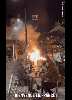 23일(이하 현지시간) 밤, 프랑스 남부 보르도에서 휘발유 폭탄과 도끼 등으로 무장한 일부 시위대가 저지른 방화에 거대한 화염이 불타오르는 동안, 화재 현장 코앞에 있는 카페에 앉아 와인을 마시며 담소를 나누는 커플의 모습