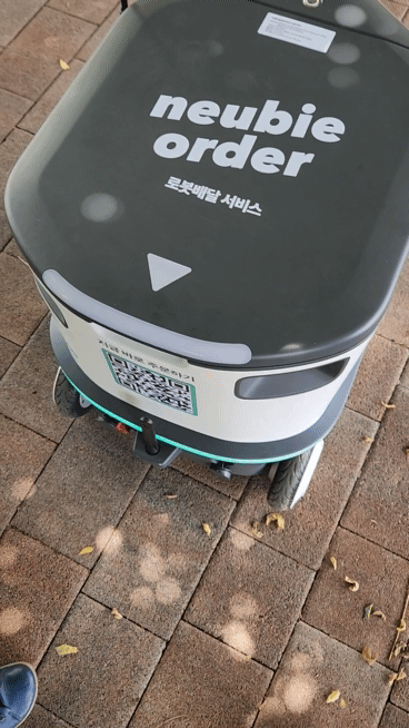 자율주행 배송 로봇 ‘뉴비’ 이용자가 주문한 제품을 꺼내고 있다. 김벼리 기자