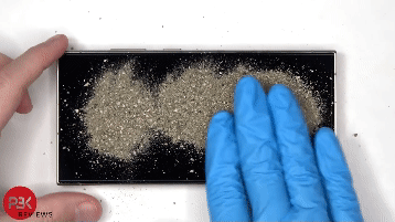 삼성전자 갤럭시S24 내구성 테스트 결과, 액정에 자갈이 섞인 흙을 뿌리고 문질러도 흠집이 나지 않았다. /유튜브 영상