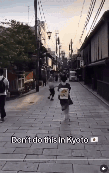 한 관광객이 일본 교토 기모노 거리에서 사진 촬영을 피하는 게이샤의 모습을 억지로 카메라에 담고 있다