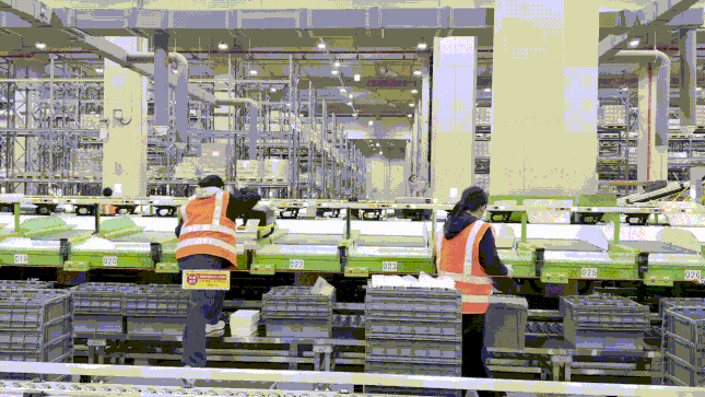 작업자들이 피스 피킹 로봇을 통해 매장별로 분류된 상품들을 PVC에 옮겨 담는 모습./사진=윤서영 기자 sy@