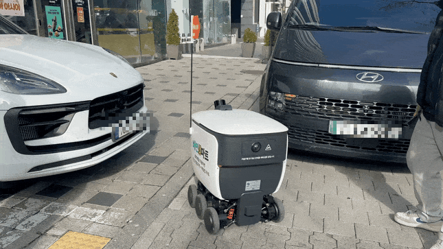 우아한형제들의 자체 배달로봇 '딜리'가 두 차량 사이를 손쉽게 빠져나가고 있다. / 사진=정혜인 기자 hij@