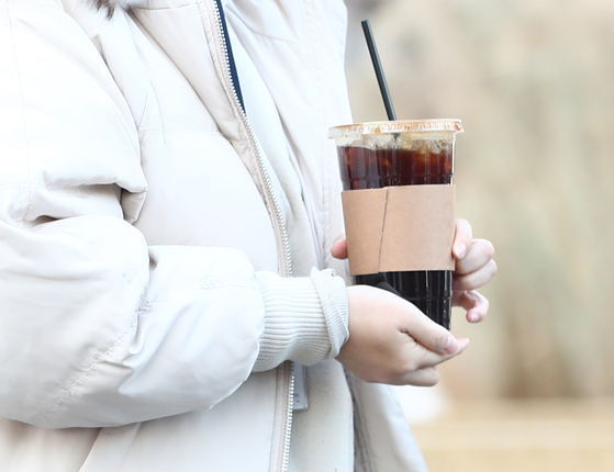 A pedestrian carries a cup of iced americano on a cold December day in Seoul in 2022 [NEWS1]