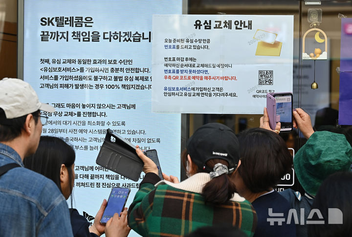 SKT 유심보호서비스 관련 안내문을 확인하는 대리점 이용자들