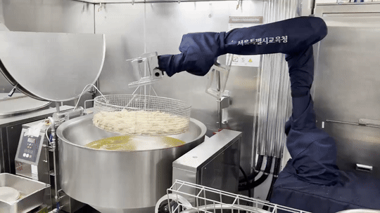 서울 영동중학교 급식실에서 조리로봇이 치킨을 튀기고 있다. 전처리된 재료를 옮겨 튀김기에 집어넣는 모습. (사진=지디넷코리아 신영빈 기자)