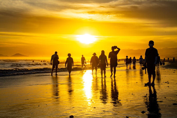A scene of tourists spending time at Dadaepo Beach as the sun sets