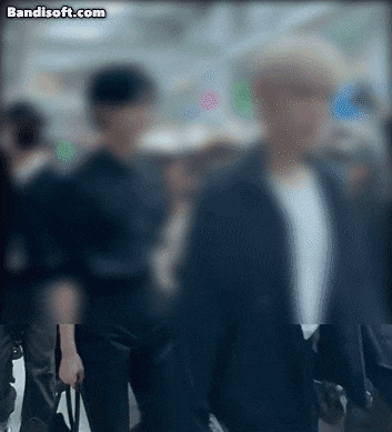 아이돌 '제로베이스원' 관계자가 인천공항에서 팬들을 밀치고 주먹을 들어올리는 모습./ 엑스