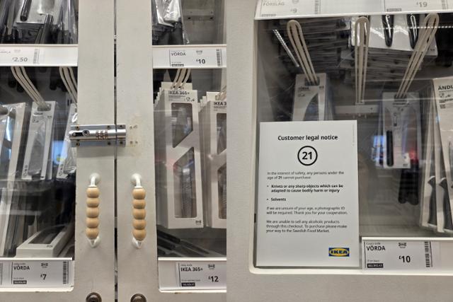 영국 매장의 잠금 처리된 식칼 진열대와 연령 제한 안내문