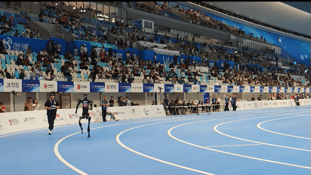 15일 열린 세계휴머노이드로봇대회에서 링이테크놀로지의 로봇이 조종수와 함께 달리고 있다. 이 로봇은 1500m를 6분34초에 달려 금메달을 목에 걸었다. 베이징=김철중 특파원 tnf@donga.com