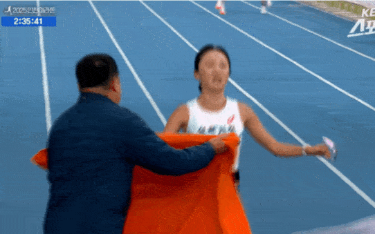 23일 인천 송도에서 열린 '2025 인천국제마라톤' 여자 국내부 경기에서 1위로 골인한 삼척시청의 이수민(오른쪽) 선수가 결승선을 통과한 직후의 모습. 김완기 감독이 이 선수에게 타월을 두르며 이 선수를 잡으려하자, 이 선수가 이를 거부하는 듯한 장면이 포착됐다. KBS스포츠 유튜브 캡처