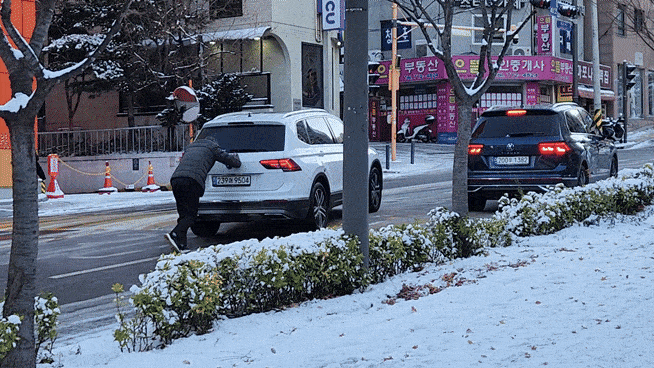 5일 오전 8시께 서울 마포구 염리동 인근 경사로가 얼어 차량이 갇히자 운전자가 손으로 차를 밀고 있다. 이영기 기자.