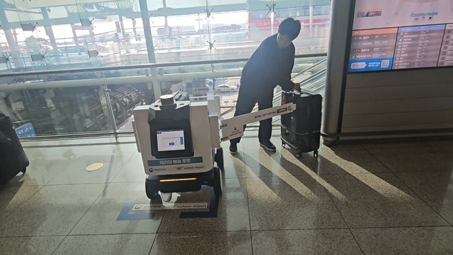 인천국제공항 출국장에서 이용객이 목적지에 도착한 수하물 배송 로봇으로부터 자신의 캐리어를 전달받고 있다. [사진=설재윤 기자]