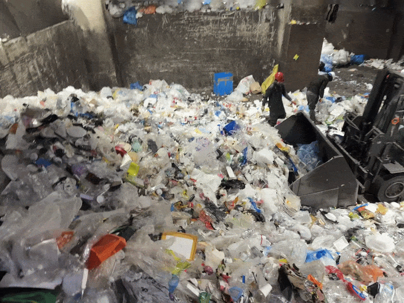 지난 4일 서울 중구 자원재활용처리장에서 노동자들이 낫으로 분리배출 봉투를 파봉하면 중장비가 쓰레기를 위쪽으로 밀어올리고 있다. 오경민 기자