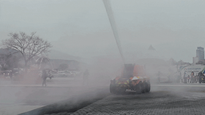 지난 25일 울산 태화강 국가정원 둔지에서 ‘레디 코리아(READY Korea) 훈련’ 중 무인소방로봇이 전기차 쪽으로 물을 살포한 뒤 소방대원들이 질식소화포를 덮고 있다. /권오은 기자