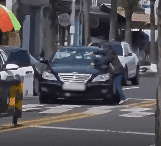 한 도로에서 한 남성이 검은색 승용차에 고무망치를 휘두르고 있다./스레드
