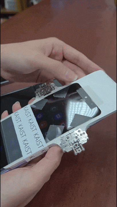 이필승 KAIST 교수 연구팀이 자신들이 개발한 ‘주름 없는 디스플레이’가 장착된 스마트폰(흰색 단말기)의 성능 시험을 하고 있다. 시판된 기존 폴더블 스마트폰(검은색 단말기) 디스플레이에서는 굵은 주름이 보인다. 이필승 KAIST 교수 연구팀 제공.