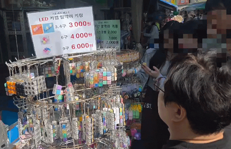 지난 24일 서울 창신동 완구거리의 한 가게 매대 앞에 있는 키캡 키링을 방문객들이 구경 중이다. /강정아 기자