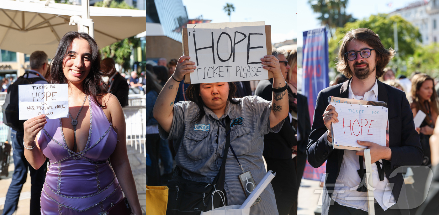 Fans hold signs seeking tickets in front of the Palais des Festivals in Cannes, France, on May 17 (local time), during the global premiere of Director Na Hong-jin's film 'Hope,' which entered the Competition section of the 79th Cannes Film Festival.