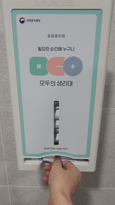 6일 오전 서울 은평구 은평통일로스포츠센터 2층 화장실 내부에 설치된 공공생리대 수동 지급기에서 기자가 생리대 한 팩을 꺼내고 있다./사진=황예림 기자