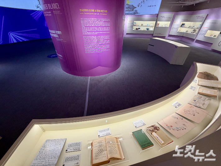 An exhibition section with manuscripts and old documents spread out inside a curved display case.